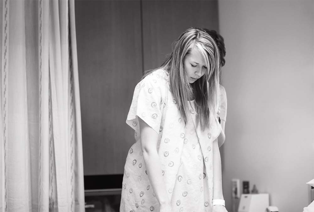 Exploration des positions d'accouchement : une femme enceinte se concentre sur sa respiration et son confort pendant le travail, en quête de la posture idéale pour la naissance. Choix position debout.