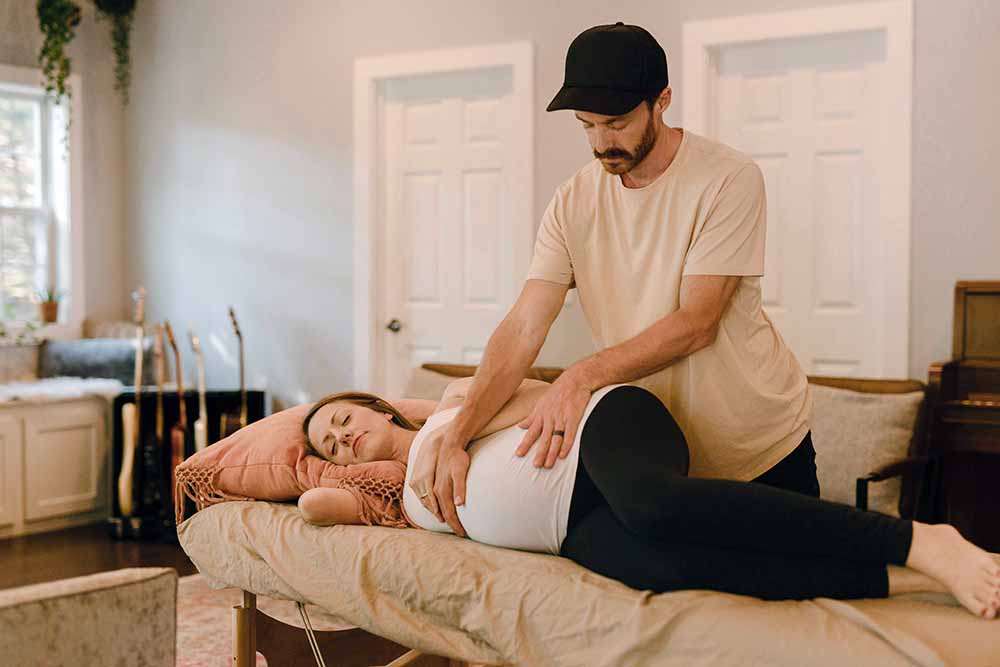 Séance de méthode Bonapace en cours, avec une femme enceinte se relaxant pendant que son partenaire applique des techniques de soutien, contribuant à la préparation pour un accouchement physiologique.