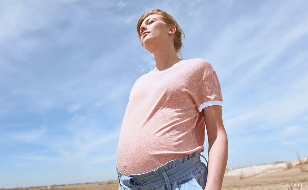 Future maman regardant le ciel sur une plage, symbolisant l'espoir et la réflexion sur le choix de la maternité et les démarches d'inscription, conseils pratiques pour s'inscrire à la maternité en fonction du terme de la grossesse.