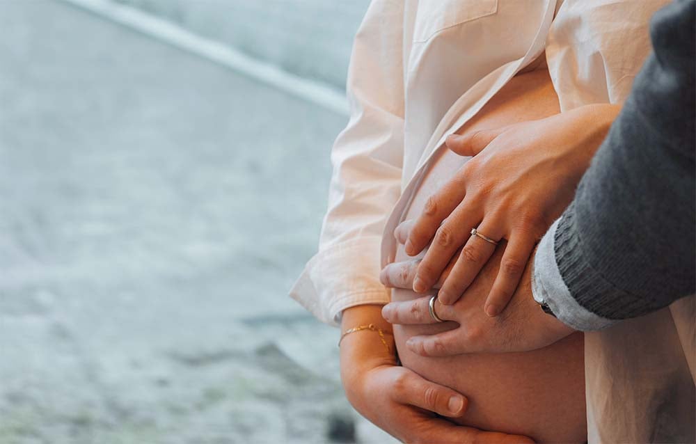 Couple touchant le ventre d’une femme enceinte, connexion avec bébé. Comment une séance préparation naissance accouchement bébé en haptonomie renforce le lien familial avant l'accouchement ?