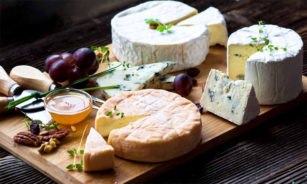 Fromages sans risque pour Noël enceinte : plateau de fromages de Noël adapté pour les femmes enceintes, avec fromages pasteurisés et accompagnements comme noix et miel. Quels fromages choisir pour Noël sans danger pendant la grossesse ?