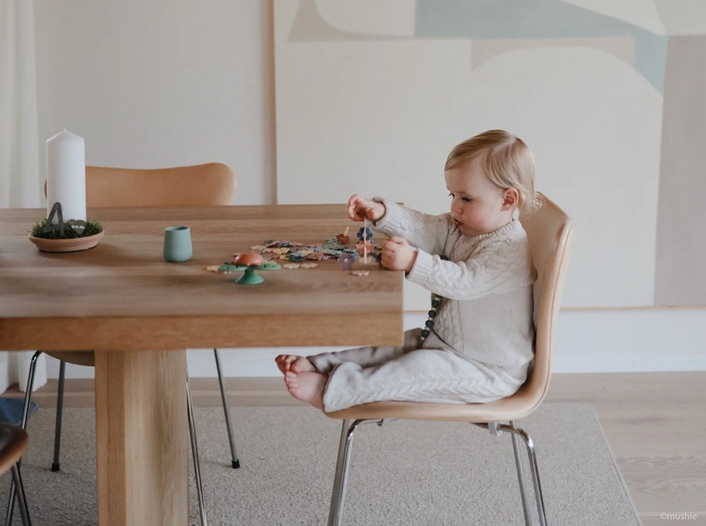 Enfant jouant avec des jouets à une table, représentant les prénoms mixtes pour bébé. Parfait pour les recherches sur les plus beaux prénoms unisexes non-genré pour bébés. Liste de prénoms.