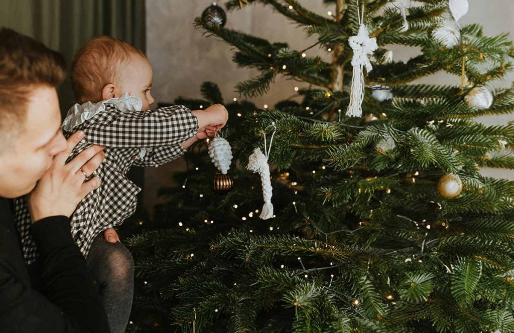 Sapin de Noël décoré pour le premier Noël d’un bébé, ambiance festive en famille. Guide d’idées cadeaux premier Noël bébé